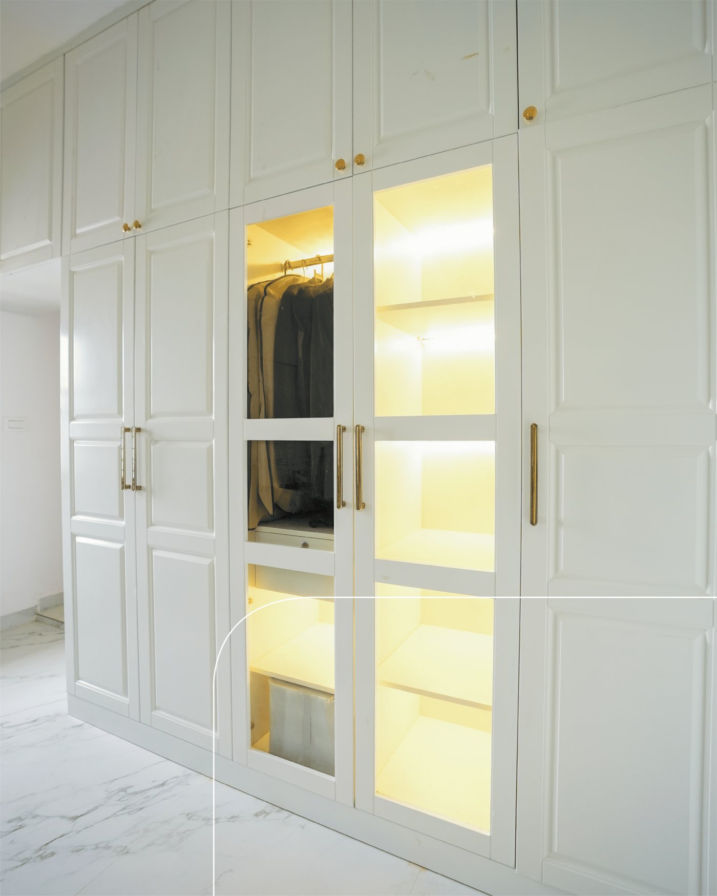 Glass-front wardrobe section with warm integrated lighting